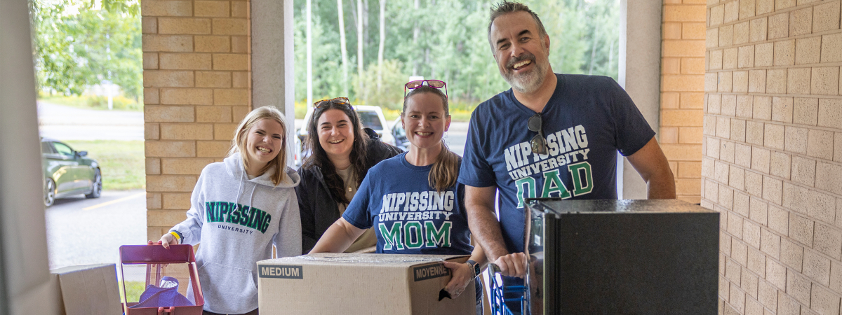 Parents and kids carrying boxes to move in to Nipissing residence
