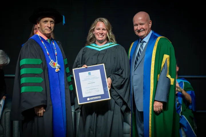 Anna Pearson receiving her award on stage from Dr. Wamsley and Dr. Cook