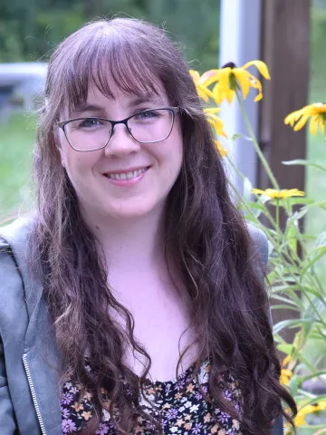 Erin Alladin poses for a portrait with a nature background