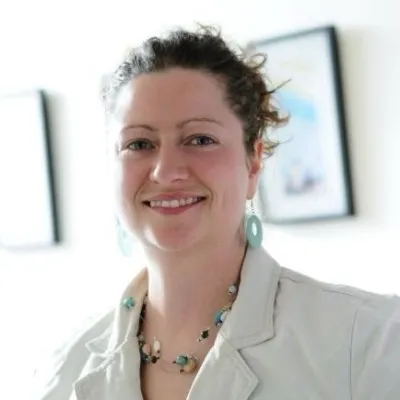 A woman in white top against a light interior background