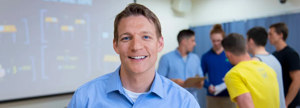 Professor in blue shirt in the foreground with a group in the background
