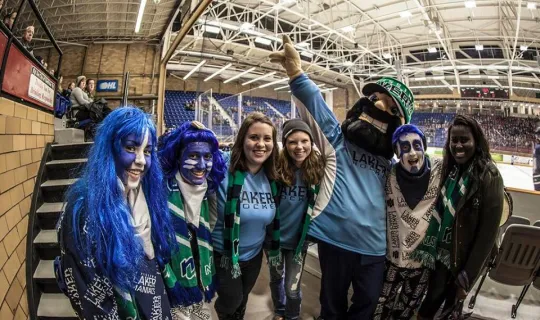 A group of Lakers in Memorial Gardens at Homecoming with Louie the Laker