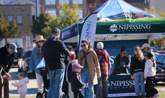 Families socializing in front of Nipissing University pop up shop during NU Homecoming 2025