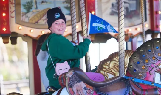 A boy in Nipissing University swag enjoying a carousel ride