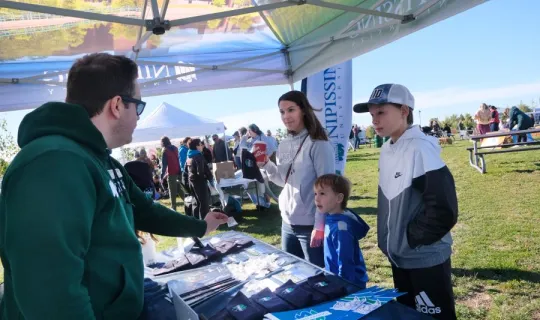 A family of 3 at Nipissing University pop up shop during NU Homecoming 2025