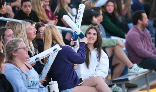 Two Lakers playing with thunder sticks during NU Homecoming 2025