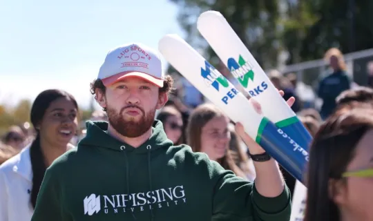 Laker is holding thunder sticks during NU Homecoming 2025