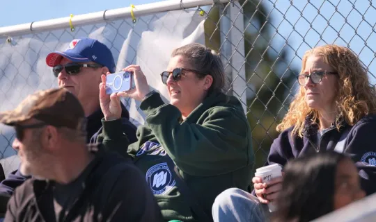 Woman is taking a picture of NU Homecoming 2025 games, others watching