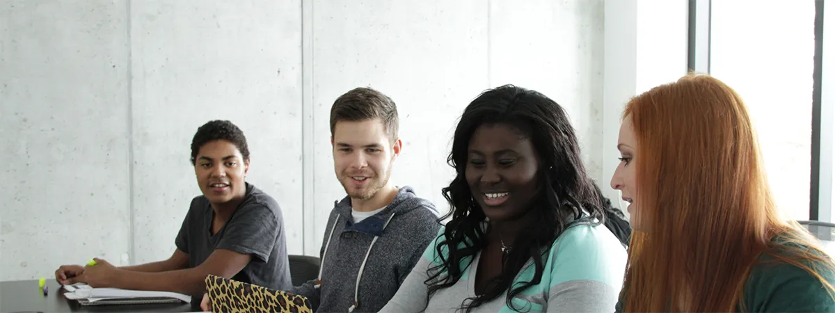 Four students seated together smiling at each other.