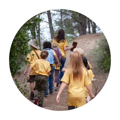 Children at camp hiking through trails as a group.