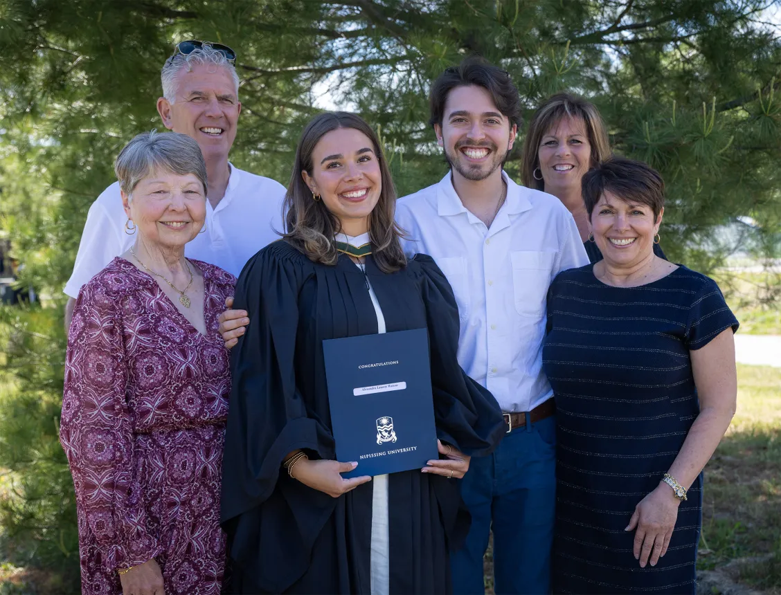 A family of parents posing with a graduate holding her degree