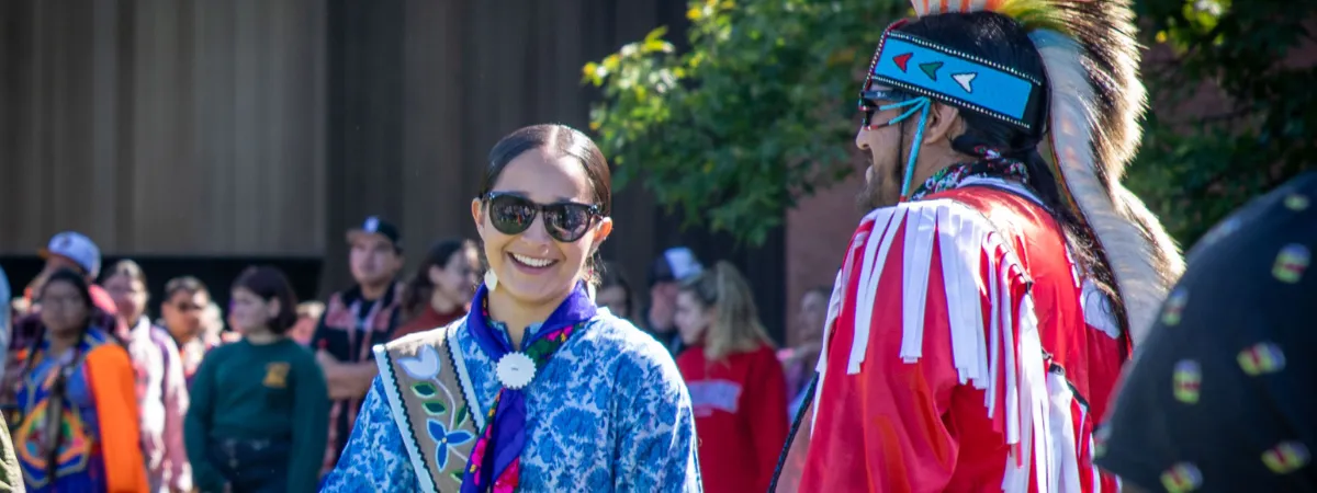 two pow wow participants donning Indigenous regalia.