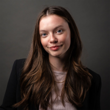 A woman in black top against a dark grey background